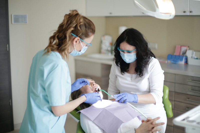 A dentist and her assistant examining the teeth of their patient.