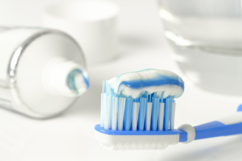 A toothbrush loaded with fluoride toothpaste — a useful tool for stopping the demineralization of teeth — lying next to an open tube of toothpaste.